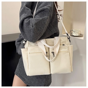 Detailed view of beige canvas tote bag with front zipper pockets and shoulder strap