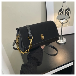 Detail of elegant black saddle bag with vintage gold chain strap and metallic twist lock
