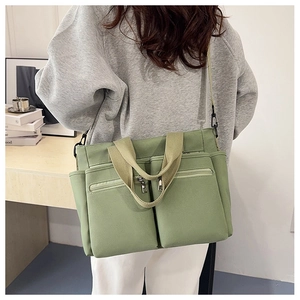 Detail of light green multi-pocket canvas tote showing water-resistant texture and zippers