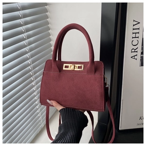 Dettaglio borsa in camoscio bordeaux con elegante chiusura dorata e manico chic