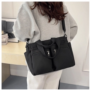 Rear view of a black multi-pocket tote bag worn cross-body showing its large capacity
