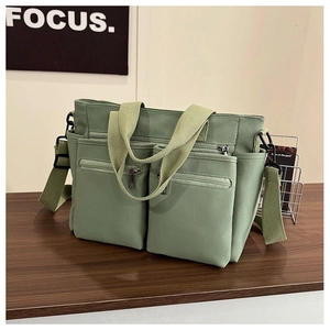 Detail view of a green canvas tote bag featuring durable handles and adjustable shoulder strap