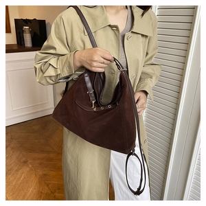 Détail d'un sac cabas en daim marron foncé avec œillets métalliques et fines brides