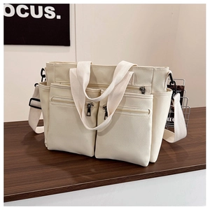 Detail of canvas tote bag showing front zipper pockets and adjustable shoulder strap