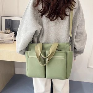 Light green canvas tote bag with multi-pocket design and adjustable shoulder strap