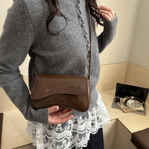 Minimalist dark brown patent leather shoulder bag with stylish wavy flap design