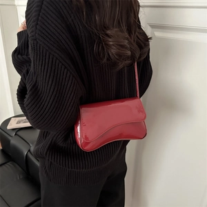 Fashionable red patent leather underarm shoulder bag with a unique asymmetric curved flap