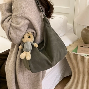 Minimalist soft leather hobo shoulder bag in dark green with a plush bear charm detail