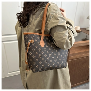 Detail of printed tote bag with monogram pattern shown on a shoulder in a stylish setting