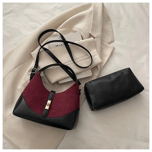 Detailed view of color-block shell bag featuring matte burgundy suede and gold metal clasp