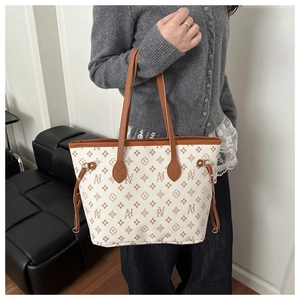 Detail of trendy tote bag with vintage monogram print and brown leather handles