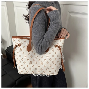 Model wearing a large monogram tote bag with brown trim and side drawstring details