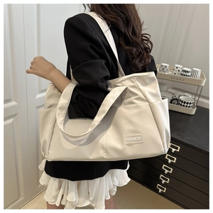 Close-up of a large beige nylon tote bag with side pockets and a fashion label