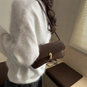 Braune Wildleder-Unterarmtasche mit Leopardenmuster und Goldverschluss am Model
