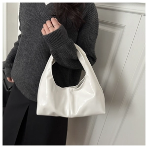 Detailed view of the glossy white faux leather finish and curved structure of the shoulder bag
