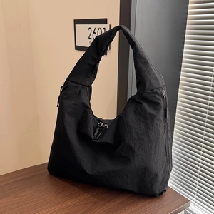 Detail shot of black nylon hobo tote featuring pleated texture and wide shoulder strap
