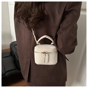 Detail view of cream suede-textured mini box bag with gold chain strap and dual zippers