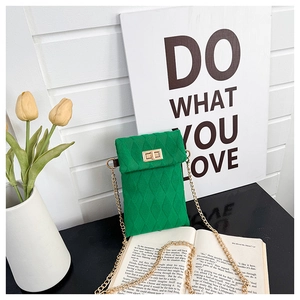 Detail of green quilted knit phone bag featuring a gold chain strap and turn-lock closure