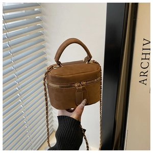 Detail of brown suede leather mini box bag with gold zipper and metal chain strap