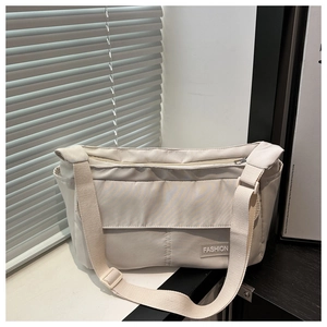 Detail of minimalist beige canvas crossbody bag featuring fashion label and adjustable strap
