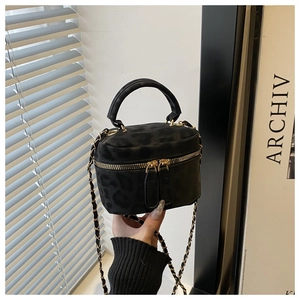 Detail of black suede-textured mini handbag featuring subtle leopard embossing and gold zipper