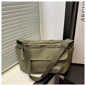 Detail of army green utility messenger bag with adjustable strap and fashion label flap
