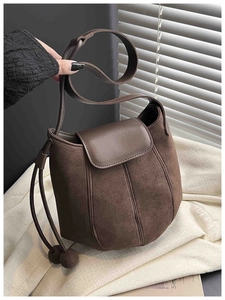 Detailaufnahme der braunen Wildleder-Beuteltasche mit Kordelzug und runden Deko-Kugeln