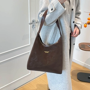Sac fourre-tout marron foncé minimaliste avec large bandoulière dans un décor moderne