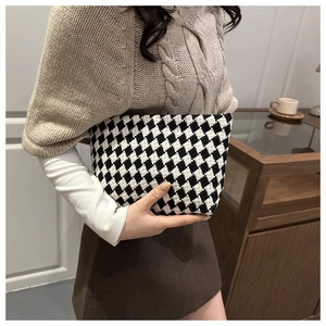 Detail of checkered knit wash bag texture shown in an indoor lifestyle setting