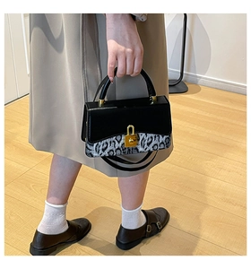 Detail of crossbody bag with leopard print panel and gold metal buckle held by model
