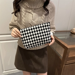 Classic black and white checkered knit handbag held by a model in a stylish beige outfit