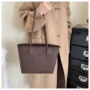 Detail of dark brown lychee leather tote bag featuring fashion text and fine stitching