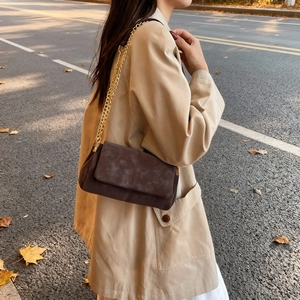Brown suede tote bag with gold chain strap shown on model in autumn street scene