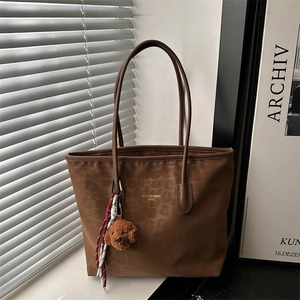 Brown leopard print tote bag with plush dog charm and gold logo for stylish commuting