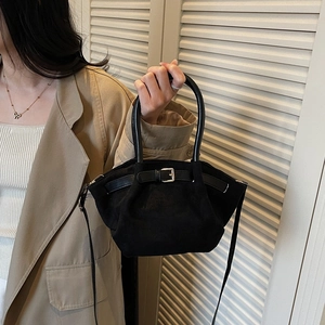 Elegant black suede crossbody bag with metal buckle and top handle shown on model
