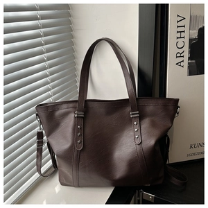 Detail of deep brown tote bag with silver star rivets and textured leather grain