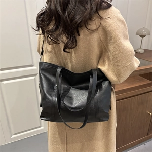 Minimalist large black leather tote bag with wide shoulder straps for commuting