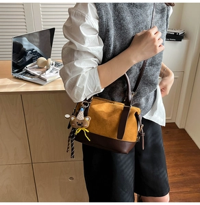 Detail der gelb-braunen Boston Bag mit Bärenanhänger in einer Lifestyle-Umgebung