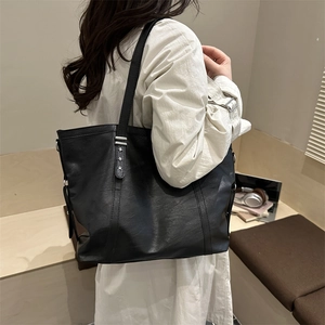 Large black faux leather tote bag with silver star studs shown from a side perspective