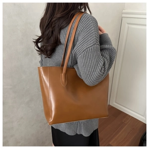 Brown PU leather tote bag with slim shoulder straps shown on model in minimalist style