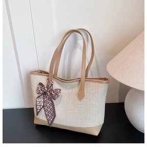 Detail of canvas tote bag featuring brown geometric silk scarf on the leather handle