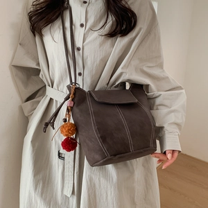 Sac seau d'hiver en daim marron foncé avec coutures blanches et pendentif pompon doux