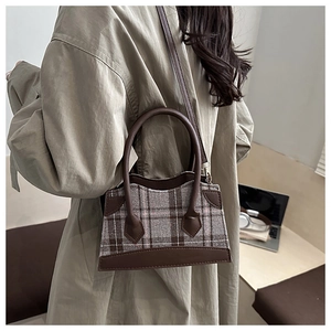 Détail du sac seau à carreaux vintage avec bordure en cuir marron et boucles en métal