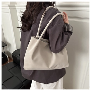 Dettaglio della borsa tote in pelle beige con cuciture eleganti e tracolla tonda morbida