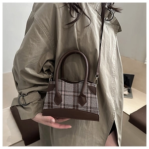Détail du tissu à carreaux gris et cuir marron foncé sur le sac trapèze vintage
