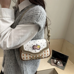 Chic checkered shoulder bag with polka dots and bow detail worn by a model in interior