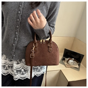 Detail of vintage brown shell-shaped crossbody bag featuring embossed heart pattern