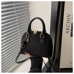 Detail of black shell crossbody bag featuring clover embossing and gold hardware accents