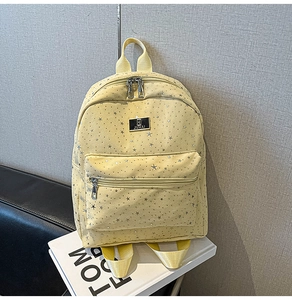 Detailed close-up of light yellow backpack with silver star print and metal logo plate