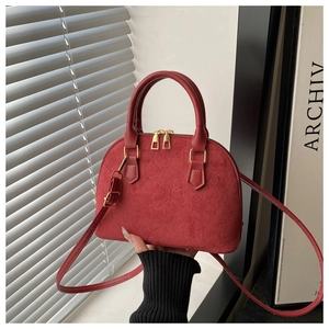 Detail of red clover-embossed shell handbag with dual golden zippers and matte finish